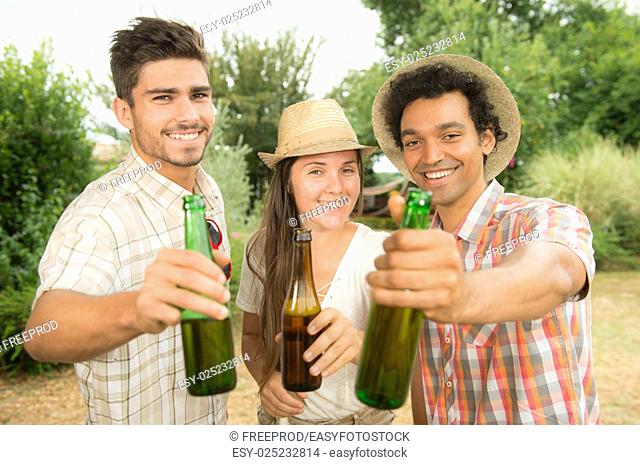 Group of friends toasting a beer bottle while preparing barbecue grill in park, France