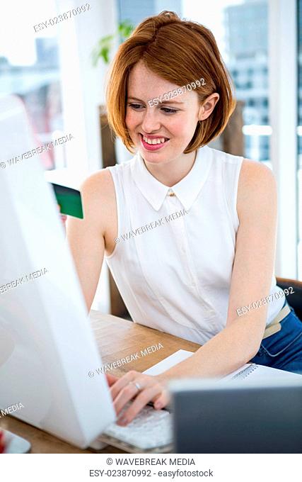 smiling hipster business woman inputting her credit card details