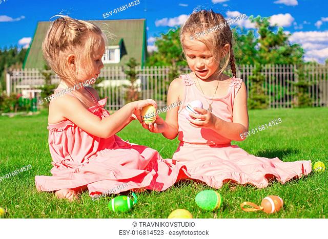 Adorable little girls playing with Easter Eggs on green grass