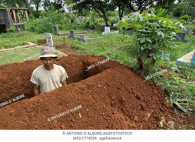 an indonesian man dig a pit in a cemetery in menteng dalam district  jakarta  indonesia  asia