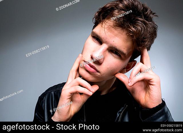 Wide angle portrait Young male model in black clothes posing in studio white background. Guy wearing black classic leather jacket