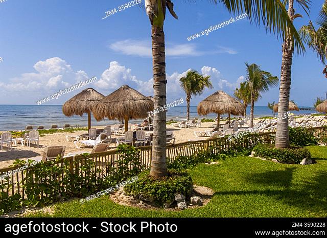 The white sand beach with Palapas at the Blue Bay Grand Esmeralda Resort along the Riviera Maya near Cancun in the State of Quintana Roo, Yucatan Peninsula
