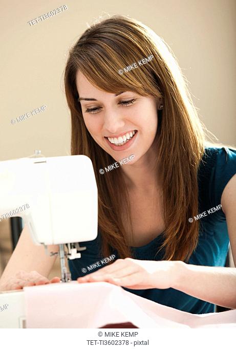 USA, Utah, Lehi, Smiling young woman using sewing machine