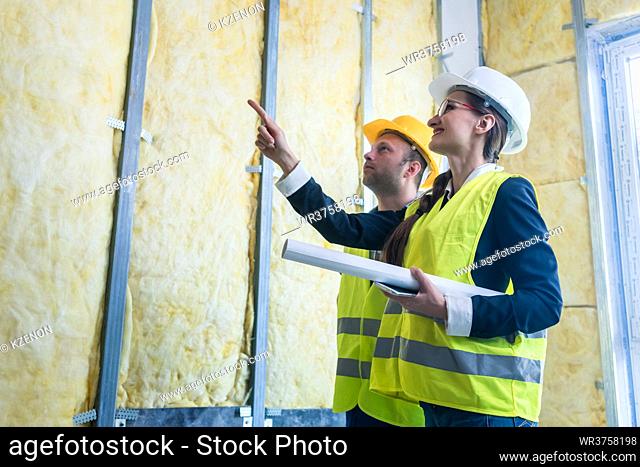 Construction manager and architect checking the insulation works in a half finished project