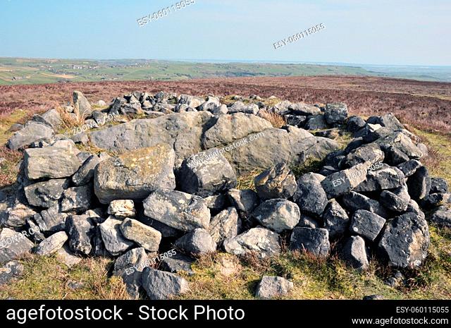 the exposed stones at the top of a cairn known as the millers grave on midgley moor in calderdale west yorkshire with surrounding pennine landscape and the...