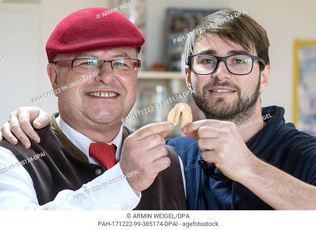 Factory owner Ralph Schaefer (L) and his son Raphael Schaefer hold up a cookie in their fortune cookie factory in Bad Abbach, Germany, 22 December 2017