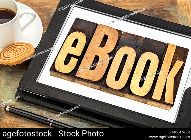 ebook (electronic book) - a word in letterpress wood type on a digital tablet with a cup of coffee