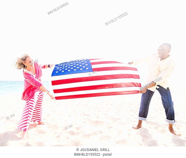 Older couple holding American flag on beach