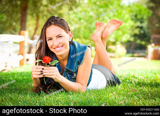 Attractive Mixed Race Girl Portrait Laying in Grass Outdoors with Flower