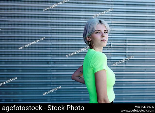 Blond woman standing in front of metal background, portrait