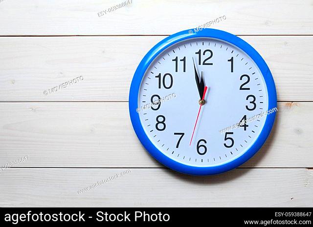 Blue wall clock with midnight new year time on wooden background