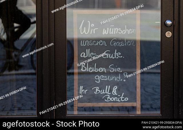 21 April 2021, Saxony, Leipzig: ""We wish our guests all the best. Stay healthy!"" is written on a board behind the entrance door of a bar in Leipzig