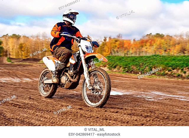 Motocross, enduro rider on dirt track. Extreme off-road race. Hard enduro motorbike. The forest behind him