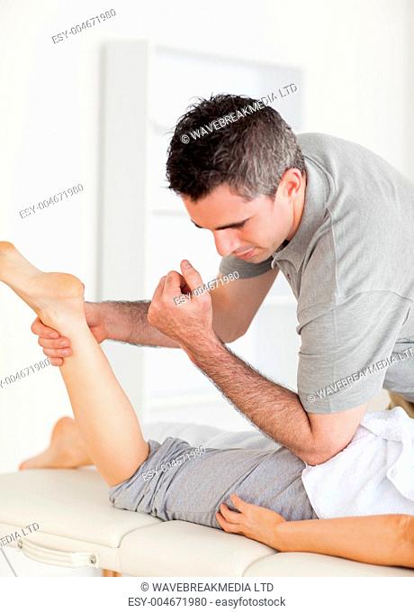 Chiropractor stretches female customer's leg