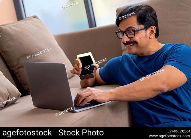 Happy man showing ring over video conference