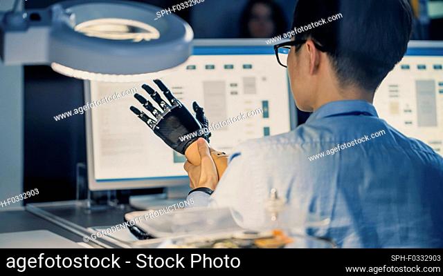 Prosthetic robot arm being tested by an engineer