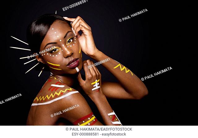 Beautiful exotic African female fashion face with tribal yellow red and white makeup cosmetics and sticks in hair