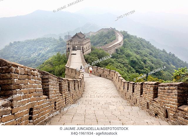 Beijing, China-August 17, 2010: Thousands of tourists visit daily the Chinese wall. A family walking on the Great Wall of China that the horizon is lost in the...