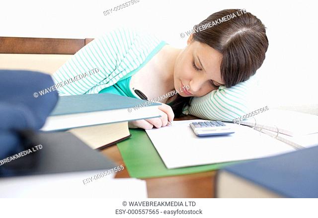 Young tired woman studying on a table in the living-room