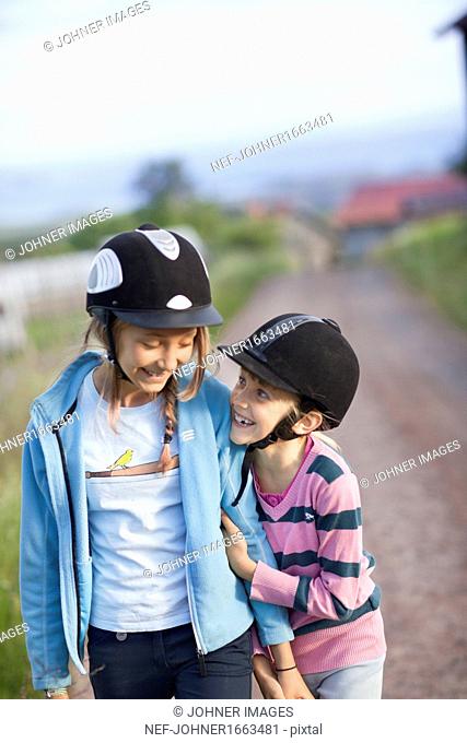 Two sisters wearing horseback riding caps