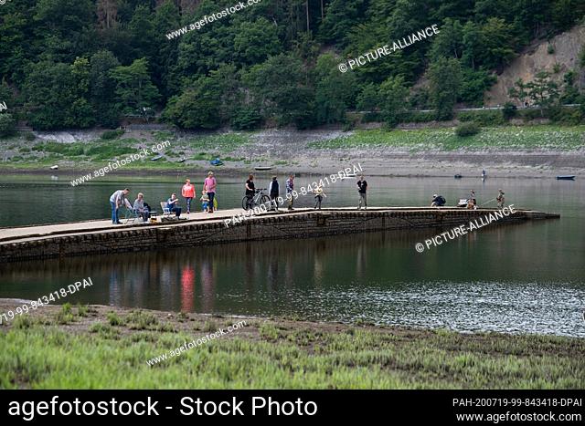 17 July 2020, Hessen, Edertal: Tourists and anglers stand and sit on the Aseler bridge in the Edersee. The water level of the North Hessian Edersee has dropped...