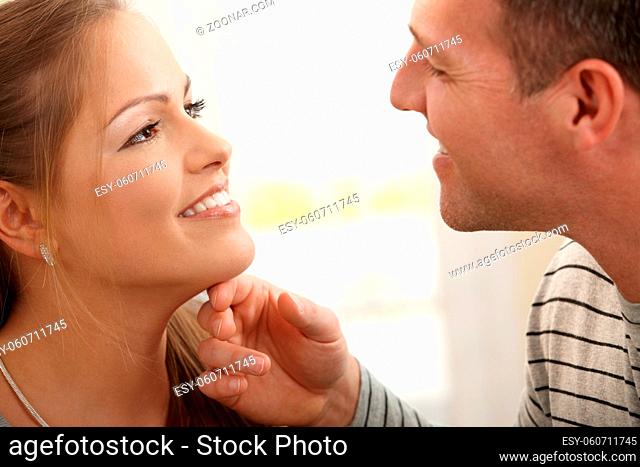 Loving couple smiling at each other, man stroking woman's neck