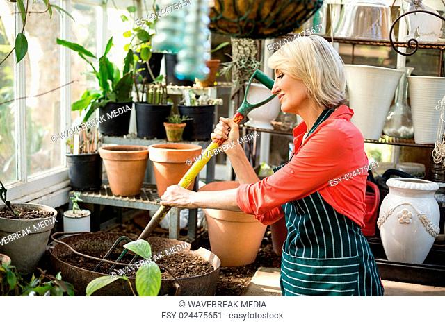 Female gardener digging soil with gardening fork