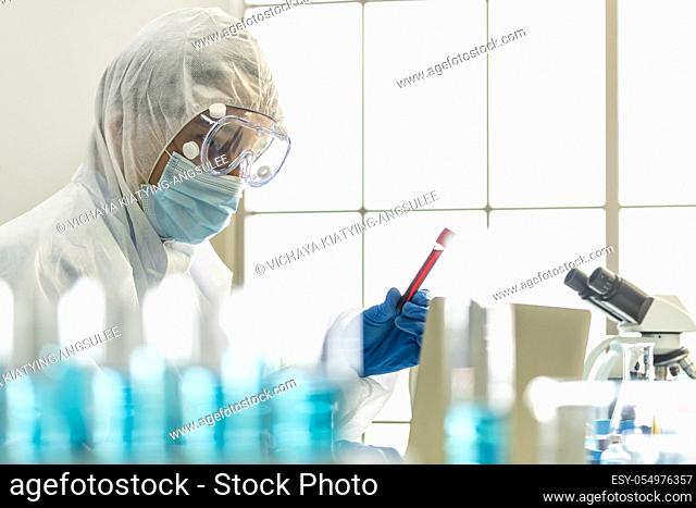Scientists hold blood sample test tube and examine for his research and develop vaccine for coronavirus covid-19 pandemic