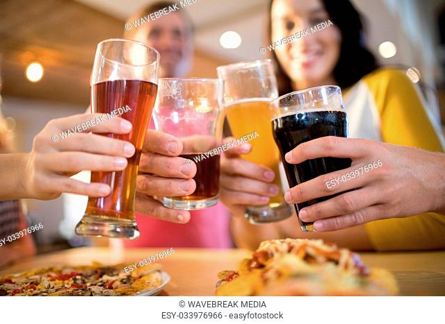 Low angle view of happy friends toasting drinks in restaurant