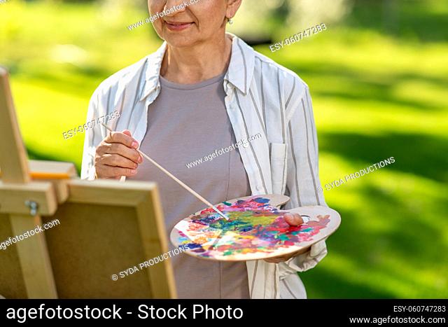 close up of woman with easel painting outdoors