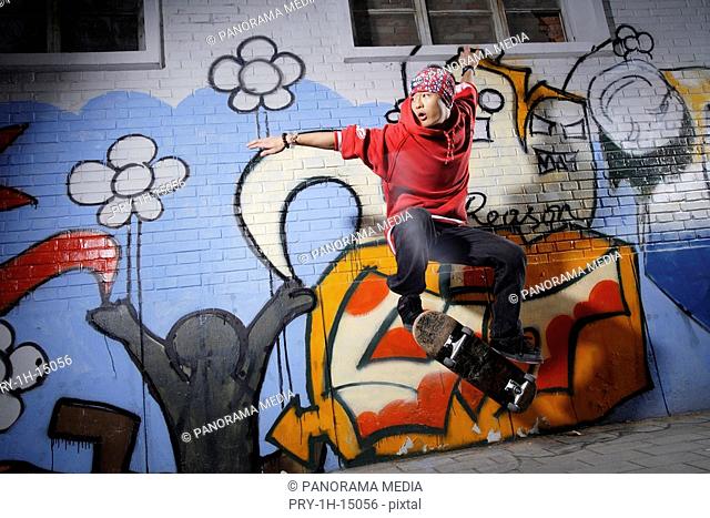 A skating-board young man in front of graffiti