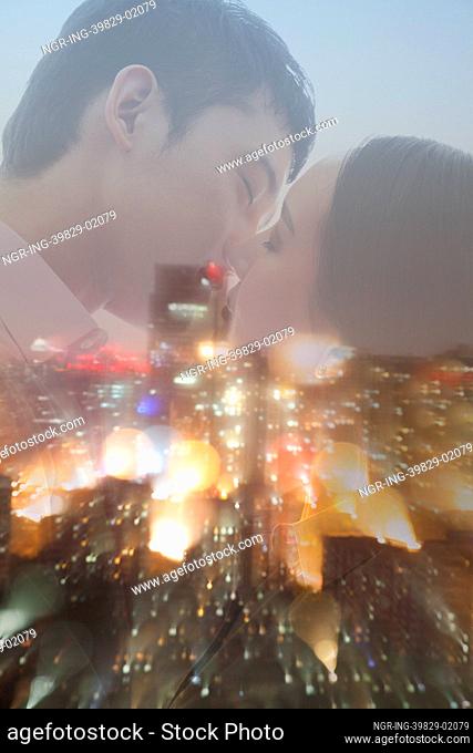 Double exposure of couple kissing over night cityscape