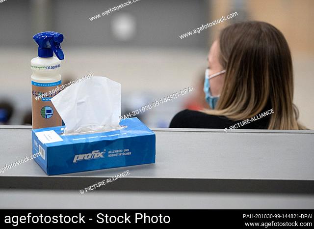 29 October 2020, Baden-Wuerttemberg, Stuttgart: A box with paper towels and a spray bottle with disinfectant is placed next to a student in the welcome event...