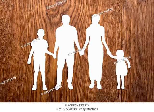 High Angle View Of Family Papercut On Wooden Desk