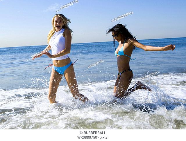 Profile of two young women wading in the sea water