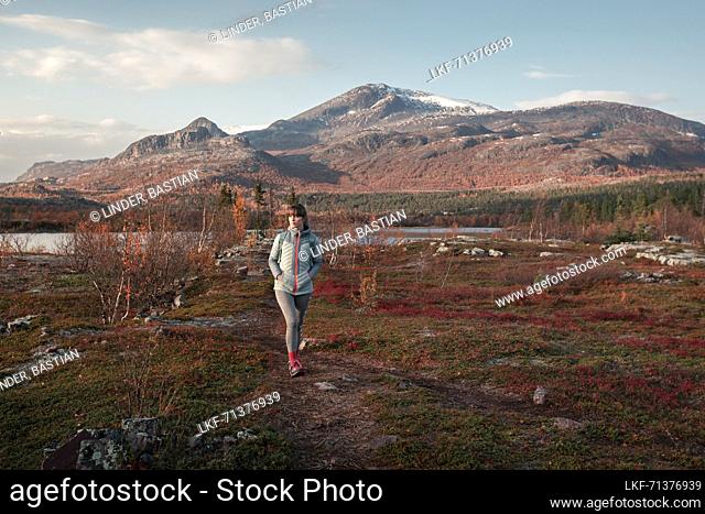 Woman hiking in landscape with mountains in Stora SjÃ¶fallet National Park in autumn in Lapland in Sweden