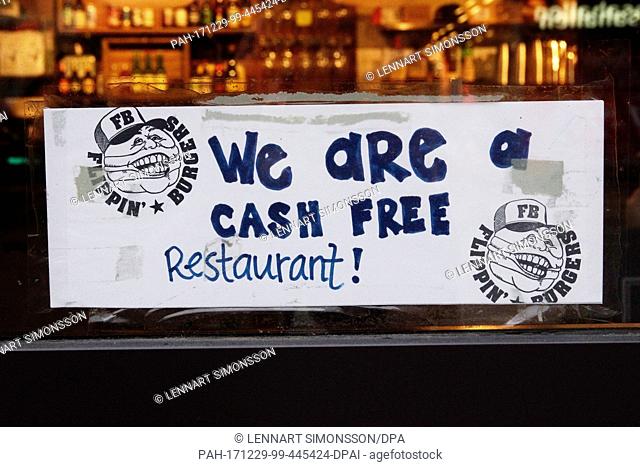 A note at the door of the burger restaurant 'Flippin Burgers' indicates that the restaurant does not accept cash in Stockholm, Germany, 20 December 2017