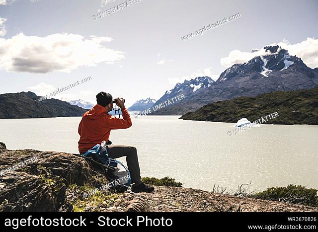 Man looking at Grey Glacier with binocular at Torres Del Paine National Park, Patagonia, Chile, South America