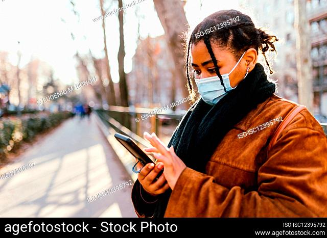 Italy, Woman in face mask texting outdoors