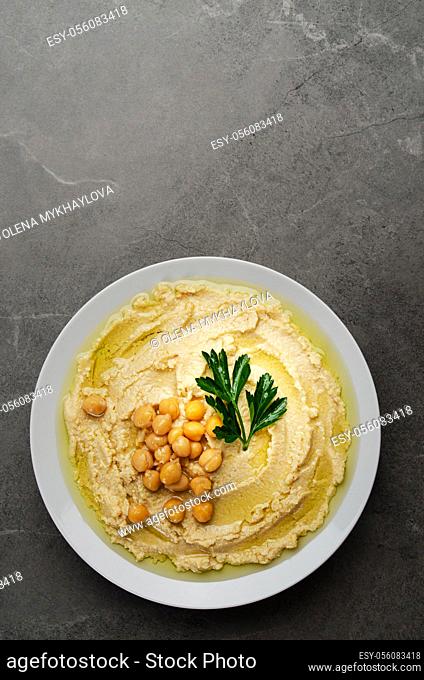 Flat lay view at hummus topped with chickpeas and green coriander leaves on stone table
