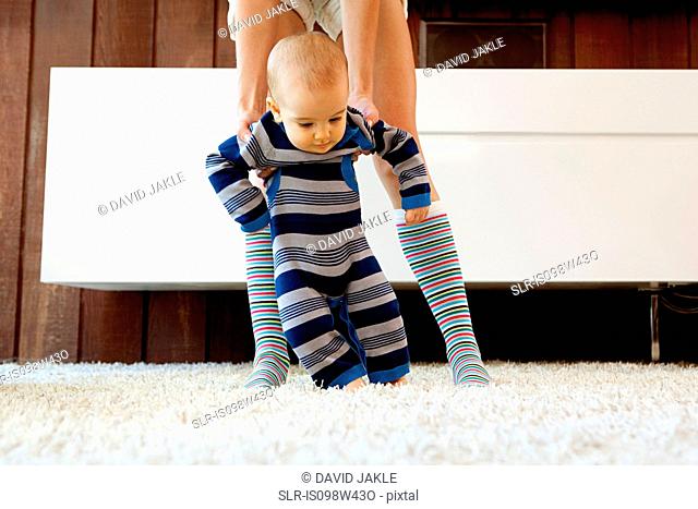 Mother helping baby son take first steps