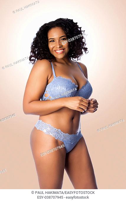 Beautiful happy plus size sexy woman with curly hair in light blue lingerie bra and thong underwear