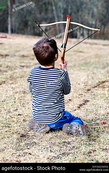 A Little boy with a crossbow in thuringia in the wood