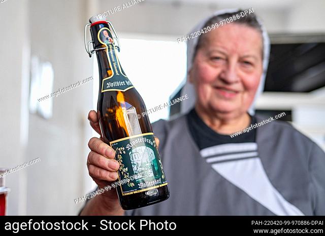 14 April 2022, Bavaria, Mallersdorf-Pfaffenberg: Sister Doris, brewmaster and nun at the Mallersdorf monastery, holds a bottle of beer in the monastery brewery