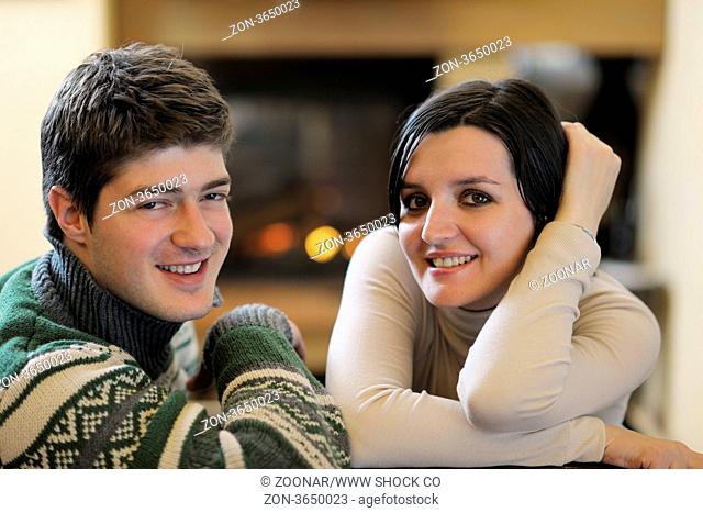 happy Young romantic couple sitting on sofa in front of fireplace at winter season in home