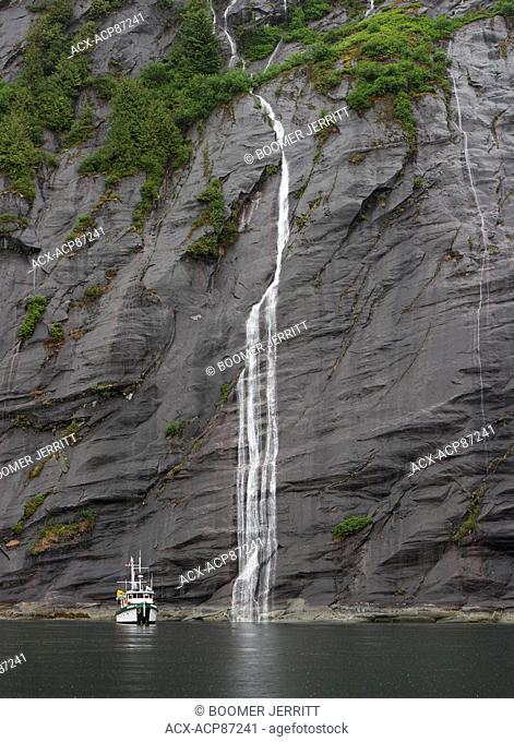 MV Columbia III is dwarfed by a cascading waterfall draining off of a granite massif in Kynoch Inlet, deep in the Great Bear Rainforest