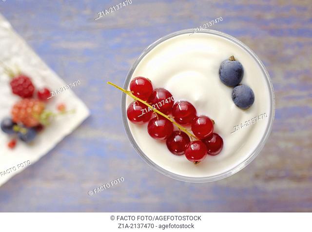 Fruit of the forest with yoghurt on a blurred blue table background