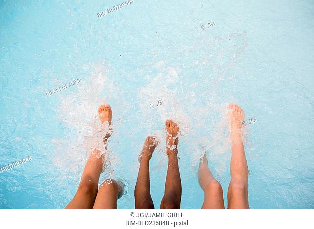 Legs of girls splashing feet in swimming pool
