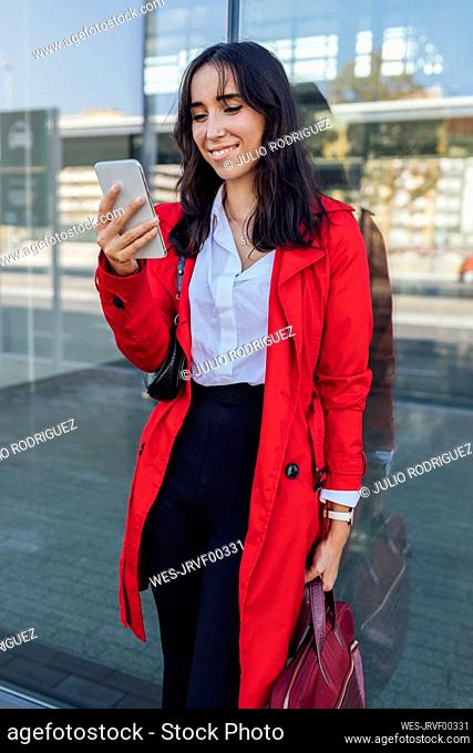 Businesswoman leaning on window while using phone