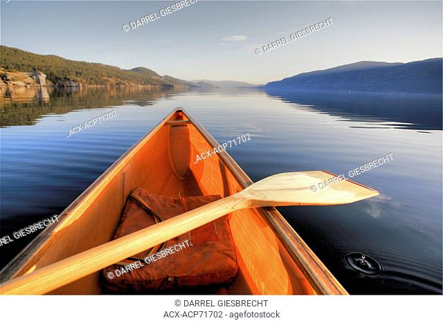 canoe on Okanagan Lake with paddle resting on it and a water droplet in the water, British Columbia, Canada, Darrel Giesbrecht